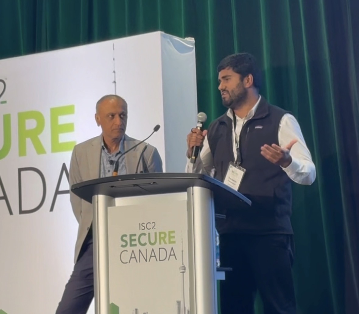 Braveenth speaking on stage with a microphone at the ISC2 Secure Canada Conference